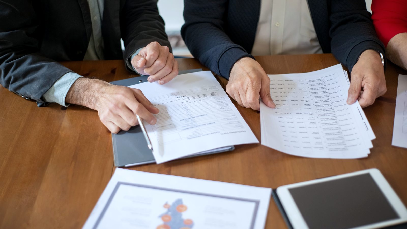 Trois personnes examinant des documents autour d'une table de travail